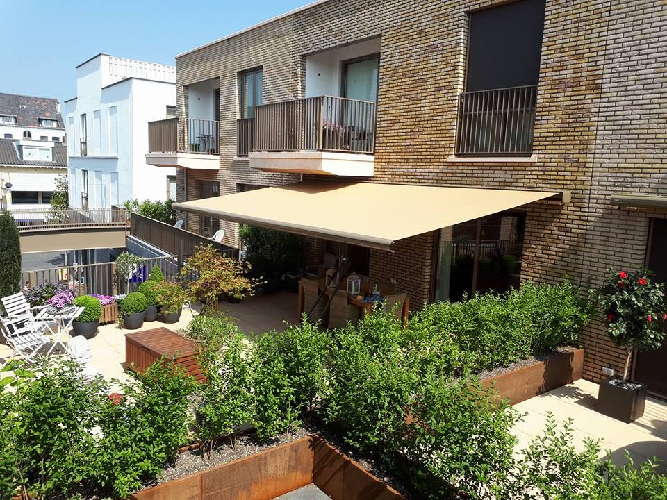 Terras met planten onder een uitstaand zonnescherm aan een woning