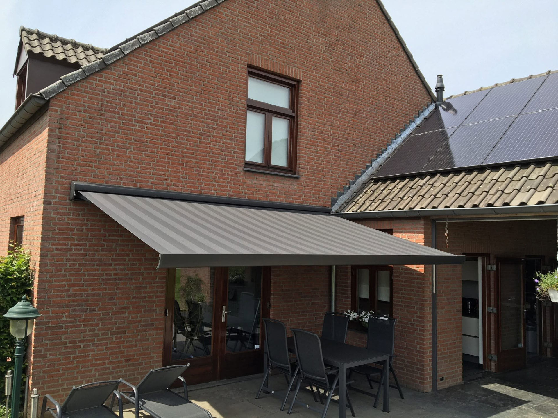 Uitstaand zonnescherm boven een terras bij een woning