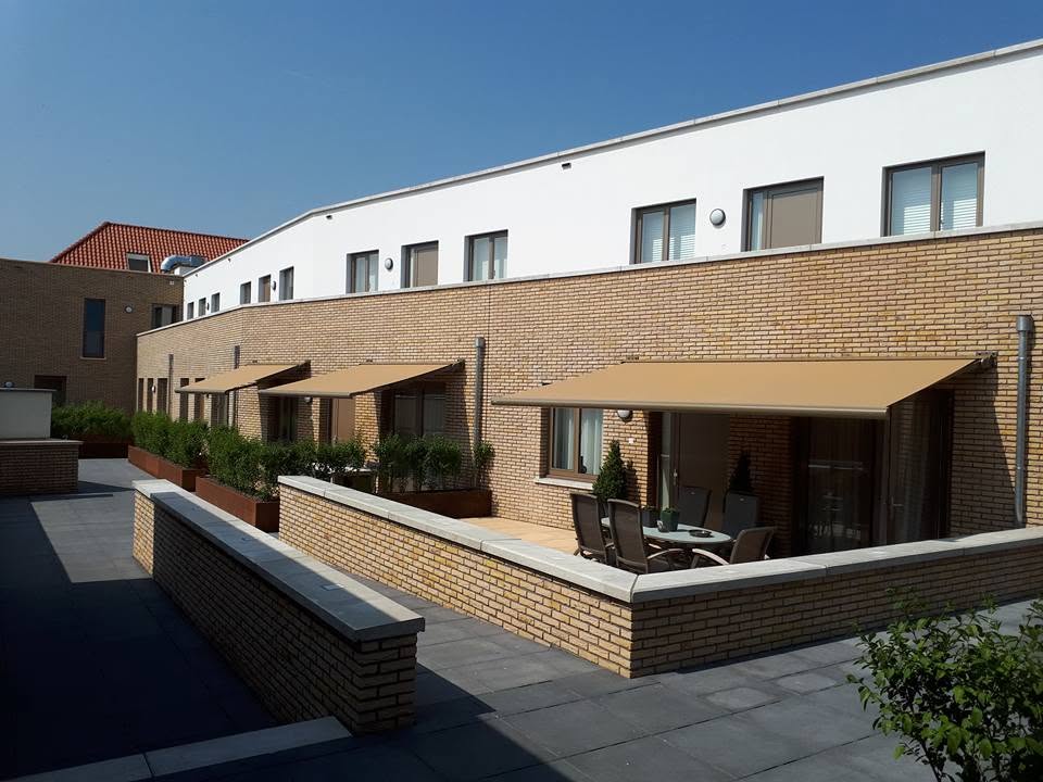 Rij woningen met meerdere uitstaande zonneschermen boven terrassen